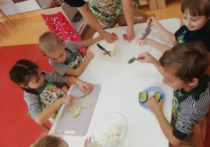 dzieci przygotowują składniki do zielonej pasty: kroją , obierają